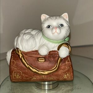 white Persian cat resting on a brown handbag